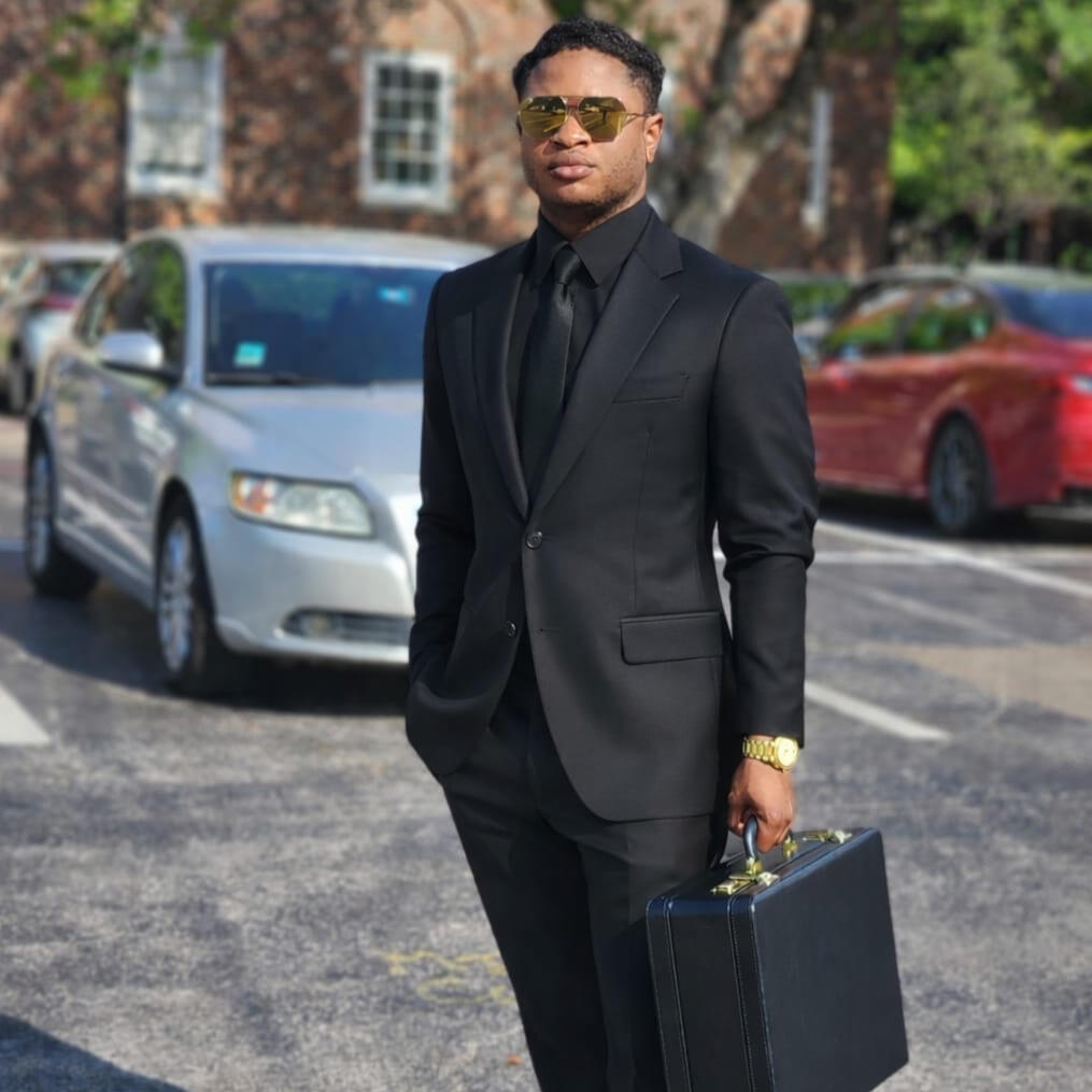 Nate Haliv wearing a black suit and carrying a black briefcase containing manuscripts for his next thriller franchise.